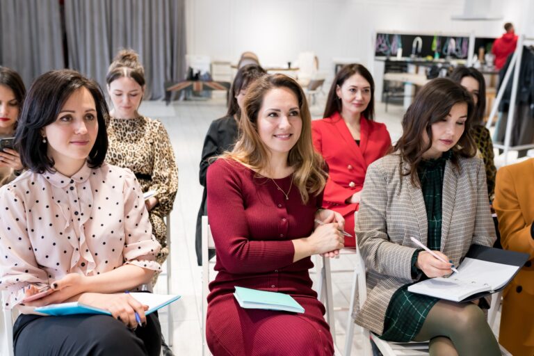 Group of females sitting in the audience for business training. Women outlining coach speech in note