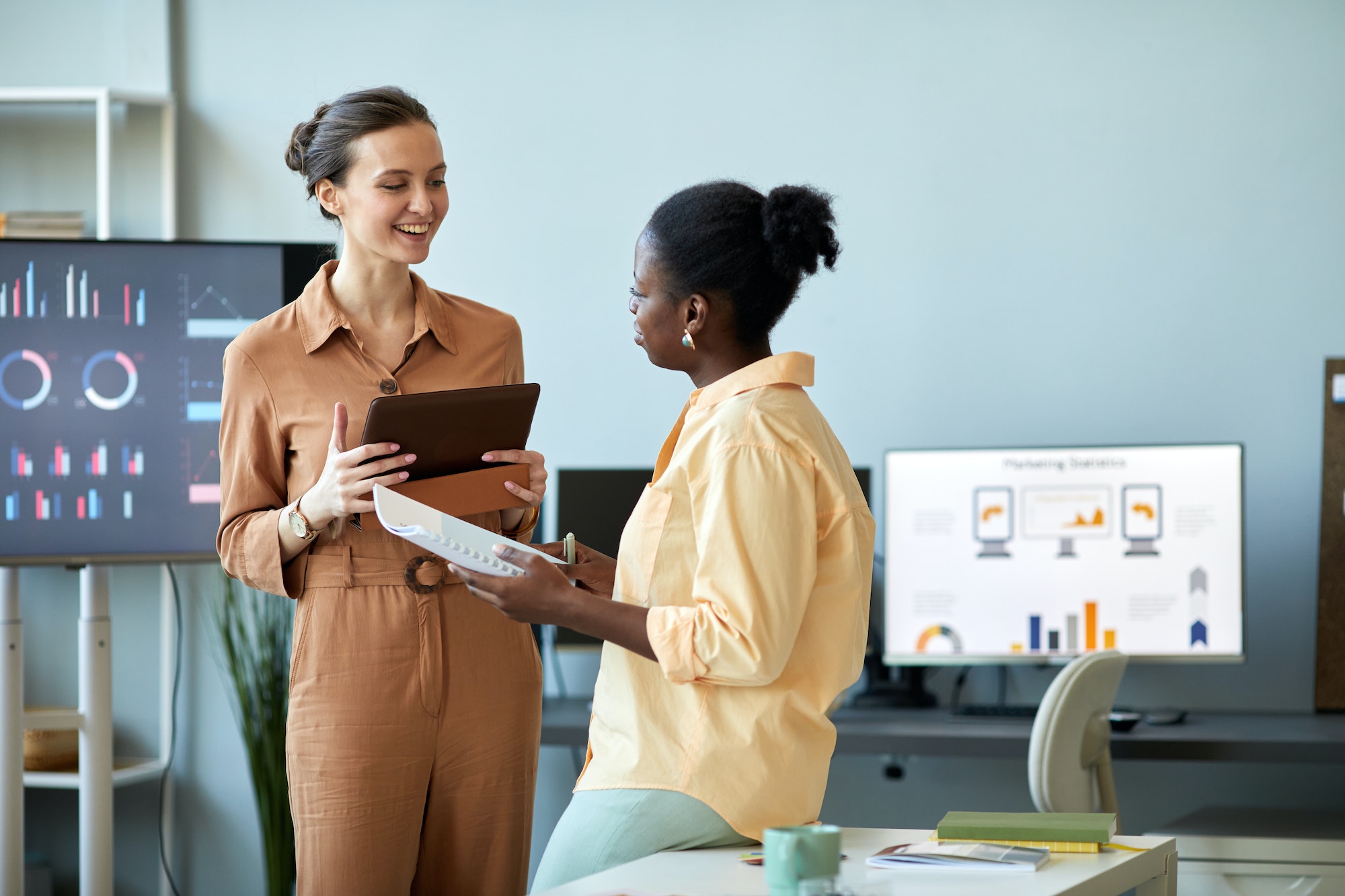 Young successful coach with tablet looking at African American female employee